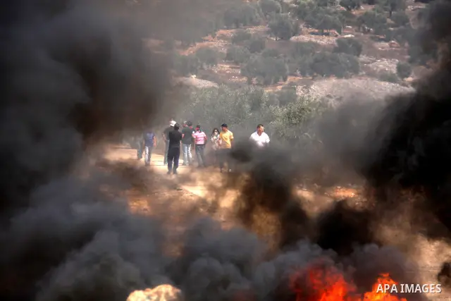 Palestinian demonstrators pass burning tires as they protest against the closure of a road during the second Intifada (uprising) by Jewish settlers from the nearby settlement of Kadumim, on September 2, 2011 in the West...