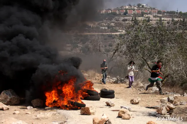 Palestinian demonstrators pass burning tires as they protest against the closure of a road during the second Intifada (uprising) by Jewish settlers from the nearby settlement of Kadumim, on September 2, 2011 in the West...