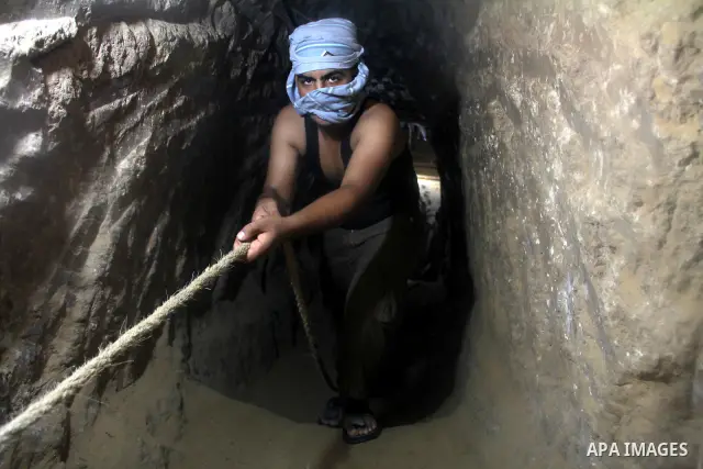 Palestinian tunnel digger, wearing a mask to conceal his identity, removes sand in a bucket from a tunnel underground in Rafah, in the southern Gaza Strip, on the border with Egypt on Sep. 4, 2011. Egyptian military Corp...