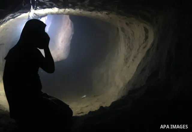 Palestinian tunnel digger, wearing a mask to conceal his identity, removes sand in a bucket from a tunnel underground in Rafah, in the southern Gaza Strip, on the border with Egypt on Sep. 4, 2011. Egyptian military Corp...