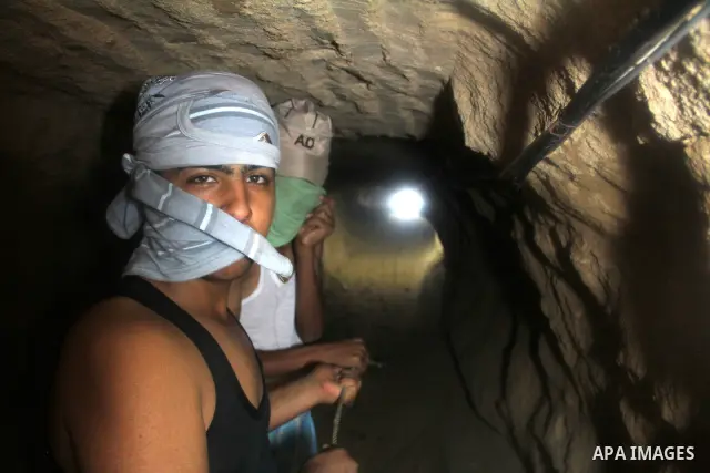 Palestinian tunnel digger, wearing a mask to conceal his identity, removes sand in a bucket from a tunnel underground in Rafah, in the southern Gaza Strip, on the border with Egypt on Sep. 4, 2011. Egyptian military Corp...