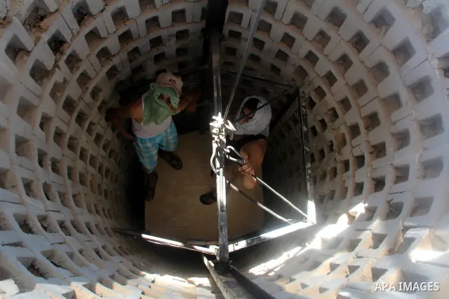 Palestinian tunnel digger, wearing a mask to conceal his identity, removes sand in a bucket from a tunnel underground in Rafah, in the southern Gaza Strip, on the border with Egypt on Sep. 4, 2011. Egyptian military Corp...