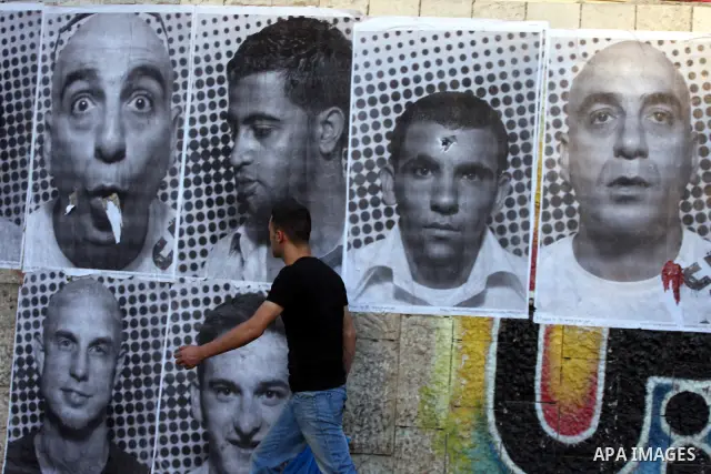 A Palestinian man walks past large black and white photographs taken by French street artist JR of Palestinians, on September 6, 2011, in the West Bank city of Ramallah. JR's project entails having Palestinian and Israel...