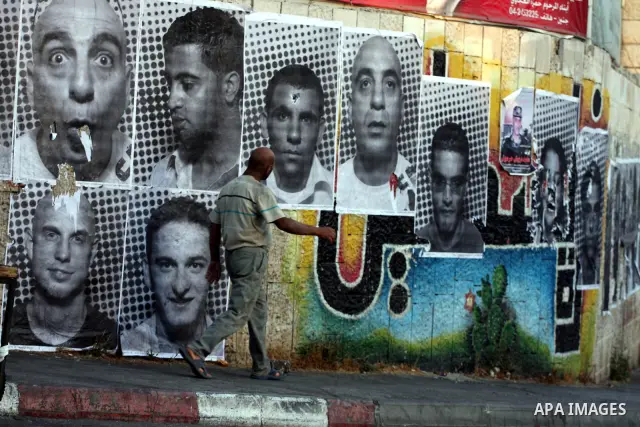 A Palestinian man walks past large black and white photographs taken by French street artist JR of Palestinians, on September 6, 2011, in the West Bank city of Ramallah. JR's project entails having Palestinian and Israel...