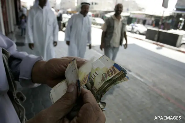 A Palestinian man exchanges currency, in the in city of Rafah the southern Gaza Strip, the U.S. dollar and shekel in black markets in the Gaza Strip on Sep. 8, 2011. Significant increase to the U.S. dollar $1000 against...