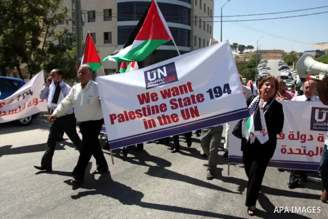 Palestinians hold banners and flags as they march during the launch of a campaign supporting a bid for Palestinian statehood recognition at the U.N, in the West Bank city of Ramallah on Sep. 8, 2011. A member of the camp...