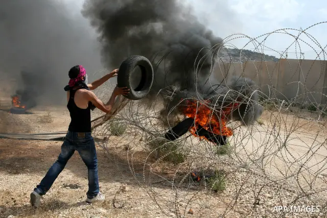 A Palestinian protester throws a tyre towards part of the controversial Israeli barrier during a demonstration in the West Bank town of Bilin, near Ramallah, Friday, Sept. 9, 2011. The Palestinians have launched a campai...