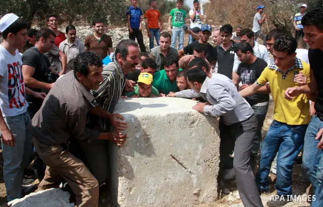 Palestinians try to remove a roadblock during the weekly protest against the settlement of Qadomim, near the village of Kofr Qadom, west of Nablus City, in the Israeli-occupied West Bank on 09 September 2011. Photo by Wa...