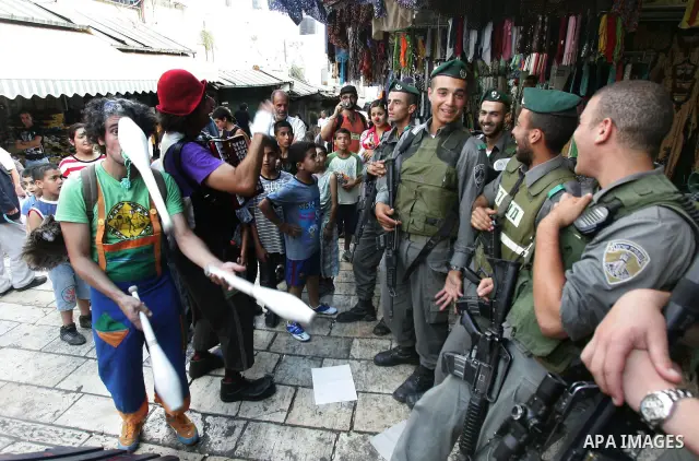 Israeli soldiers look at performers with the international "Festiclown" group as they entertain passers-by near Damascus Gate in Jerusalem's Old City on September 9, 2011, as part of the first international clown festiva...