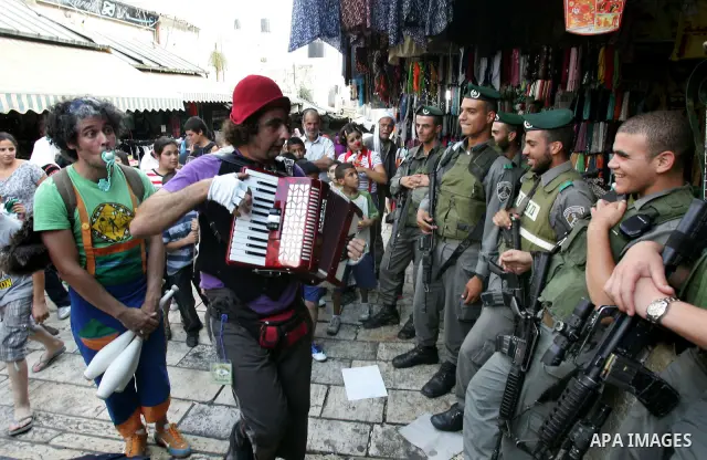 Israeli soldiers look at performers with the international "Festiclown" group as they entertain passers-by near Damascus Gate in Jerusalem's Old City on September 9, 2011, as part of the first international clown festiva...