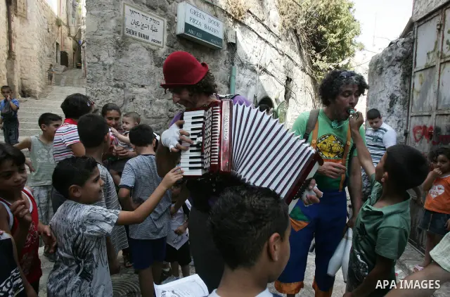 Performers with the international "Festiclown" group entertain passers-by outside Damascus Gate in Jerusalem's Old City on September 9, 2011, as part of the first international clown festival in the Palestinian territori...