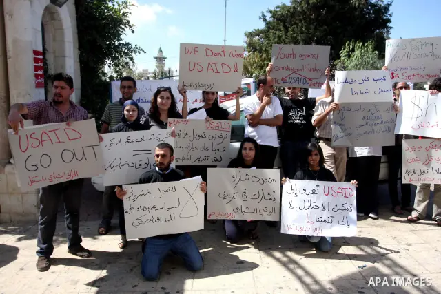 Palestinian youths hold placards bearing anti US and USAID slogans during a protest against United States policies in regard to the Palestinian-israeli conflict in the West Bank city of Ramallah on September 10, 2011. Ph...