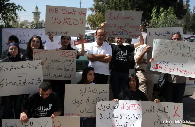 Palestinian youths hold placards bearing anti US and USAID slogans during a protest against United States policies in regard to the Palestinian-israeli conflict in the West Bank city of Ramallah on September 10, 2011. Ph...