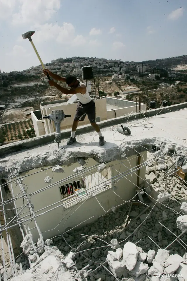 Palestinian Jerusalem resident Adnan Taha destroys his own home with a fellow Palestinian in Arab east Jerusalem on September 11, 2011, in implementation of an Israeli court order which ruled that the house was built wit...