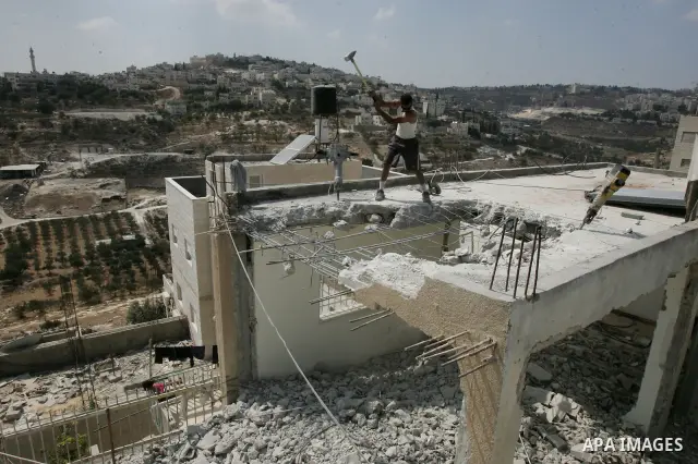 Palestinian Jerusalem resident Adnan Taha destroys his own home with a fellow Palestinian in Arab east Jerusalem on September 11, 2011, in implementation of an Israeli court order which ruled that the house was built wit...