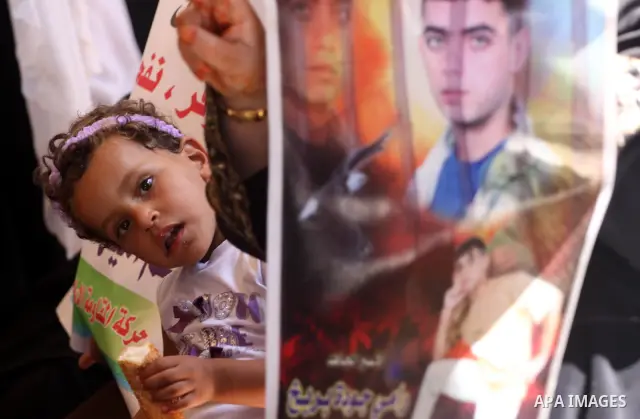 A Palestinian girl with her mother hold pictures of their prisoned relatives in Israeli jails as they gather in a weekly activity calling for their liberty at the Red Cross headquarters in Gaza City on Sep. 12, 2011. Abo...