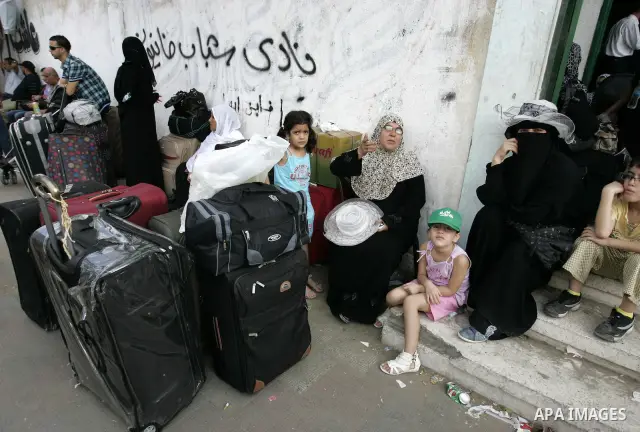 Palestinians sit near their luggage as they wait to cross into Egypt through the Rafah border crossing in the southern Gaza Strip on Sep 12, 2011. Photo by Abed Rahim Khatib