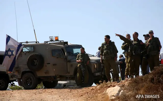 Israeli soldiers inspect the area after a Palestinian vineyard was damaged by suspected Jewish settlers from the nearby settlement Karmi Tasour in the West Bank village of Beit Omar, near Hebron on 12 September 2011. Med...