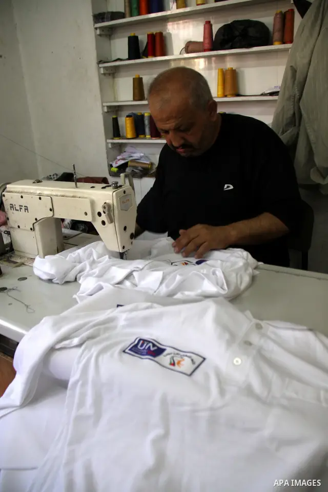 A Palestinian tailor sews United Nation logo on Shirts to be used in the national campaign to promote the Palestinian bid to obtain statehood recognition at the United Nations, at a factory in the West Bank city of Nablu...