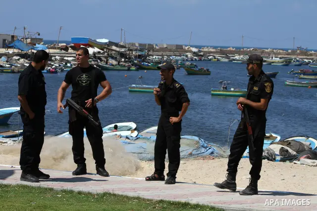 Palestinian policemen stand while the students hold the pictures of Turkish Prime Minister Recep Tayyip Erdogan and the Turkish and Palestinian flags during rally beckoning him to visit the Gaza Strip at the port in Gaza...
