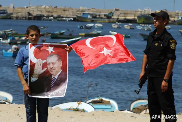 A Palestinian student holds the pictures of Turkish Prime Minister Recep Tayyip Erdogan and the Turkish and Palestinian flags during rally beckoning him to visit the Gaza Strip at the port in Gaza City on Sep. 13, 2011....