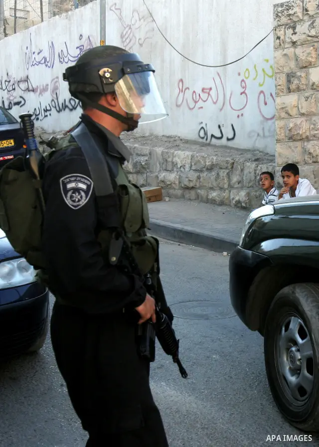 Palestinian children sit past Israeli riot policeman standing guard in the east Jerusalem neighborhood of Silwan on Sep. 13, 2011 following brief clashes between police and Palestinian stone throwers. Photo by Mahfouz Ab...