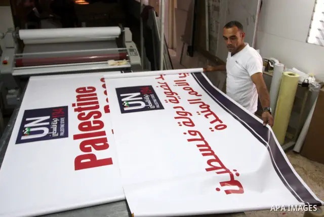 A Palestinian worker inspects a banner as it prints in the West Bank city of Ramallah September 13, 2011. A grass-root campaign supporting the upcoming Palestinian bid at the United Nations is gearing up for the diplomat...