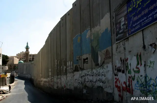 Palestinians walk past a section of Israel's controversial concrete barrier that separates the West Bank from Jerusalem on September 14, 2011. in Abu Dis, in Israeli-annexed east Jerusalem. Photo by Mahfouz Abu Turk