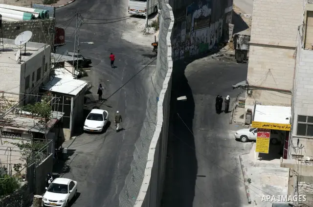 Palestinians walk past a section of Israel's controversial concrete barrier that separates the West Bank from Jerusalem on September 14, 2011. in Abu Dis, in Israeli-annexed east Jerusalem. Photo by Mahfouz Abu Turk