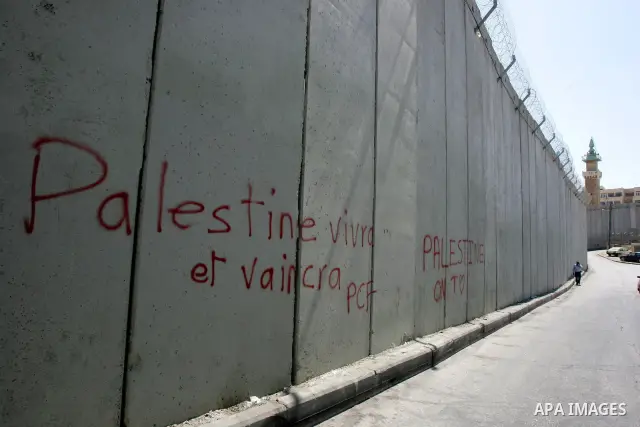 Palestinians walk past a section of Israel's controversial concrete barrier that separates the West Bank from Jerusalem on September 14, 2011. in Abu Dis, in Israeli-annexed east Jerusalem. Photo by Mahfouz Abu Turk
