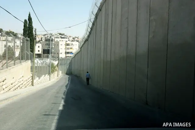 Palestinians walk past a section of Israel's controversial concrete barrier that separates the West Bank from Jerusalem on September 14, 2011. in Abu Dis, in Israeli-annexed east Jerusalem. Photo by Mahfouz Abu Turk