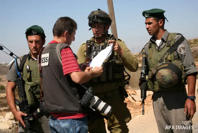 Israeli soldiers speak with a photographer as Palestinian and international activists work on a Palestinian's farm land in the West Bank village of Beit Omar near Hebron, 16 September 2011. The Israeli soldiers eventuall...