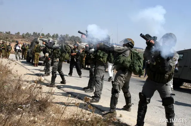 Israeli soldiers shoot tear gas canisters toward Palestinian demonstrators during a protest against the expansion of the nearby Jewish settlement of Halamish, in the West Bank village of Nabi Saleh, near Ramallah, Friday...
