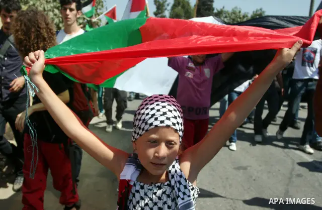 Palestinian demonstrators and international activists wave with Palestinian flag during a protest against the expansion of the nearby Jewish settlement of Halamish, in the West Bank village of Nabi Saleh, near Ramallah,...