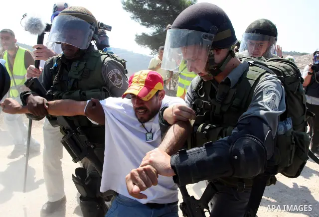 Israeli soldiers detain a Palestinian demonstrator during a protest against the expansion of the nearby Jewish settlement of Halamish, in the West Bank village of Nabi Saleh, near Ramallah, Friday, Sept. 16, 2011. Photo...