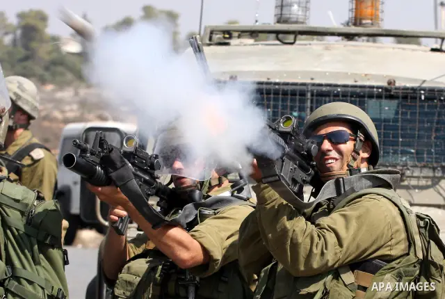Israeli soldiers shoot tear gas canisters toward Palestinian demonstrators during a protest against the expansion of the nearby Jewish settlement of Halamish, in the West Bank village of Nabi Saleh, near Ramallah, Friday...