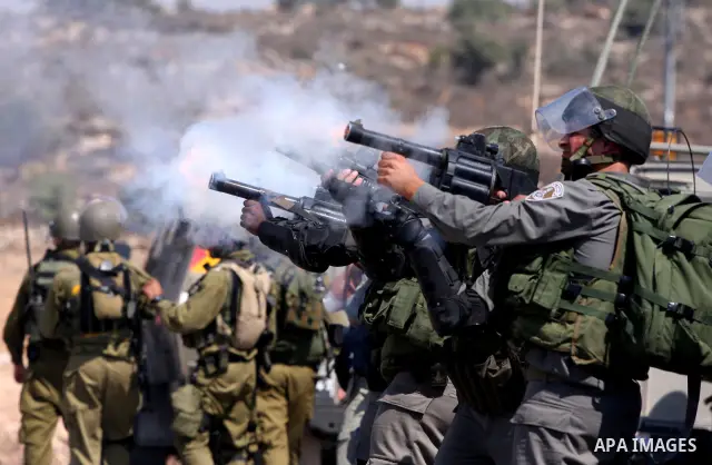 Israeli soldiers shoot tear gas canisters toward Palestinian demonstrators during a protest against the expansion of the nearby Jewish settlement of Halamish, in the West Bank village of Nabi Saleh, near Ramallah, Friday...
