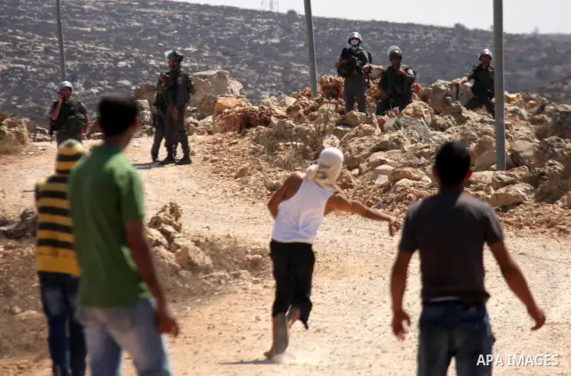 Palestinians hurl rocks at Israeli soldiers during clashes at Qusra village near the West Bank city of Nablus on 16 September 2011. Israeli settlers assaulted the village Friday morning, leading to clashes with Israeli f...