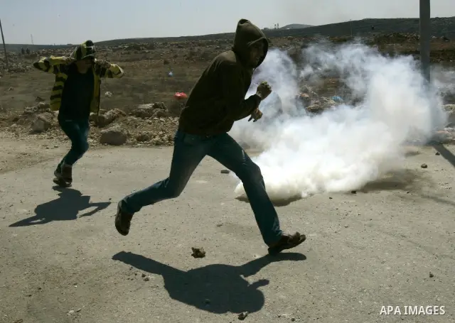 Palestinians take cover from tear gas during clashes at Qusra village near the West Bank city of Nablus on 16 September 2011. Israeli settlers assaulted the village Friday morning, leading to clashes with Israeli forces...