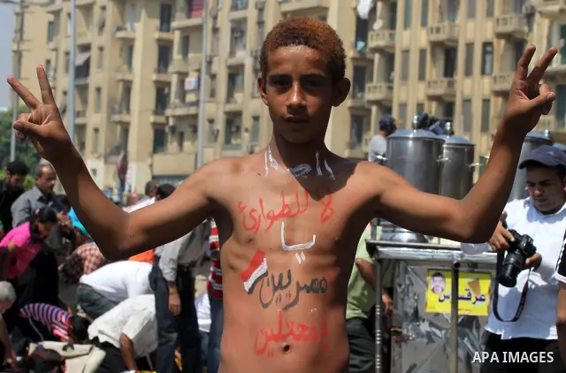 An Egyptian boy paints the Egyptian flag and logos on his body at Tahrir Square while hundreds of Egyptians demonstrate against the expansion of the Emergency Law at Al Tahrir Square. The law allows censorship, governmen...