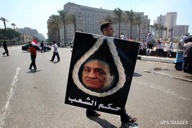 An Egyptian youth holds a poster showing former Egyptian President Hosni Mubarak on a noose at Tahrir Square while hundreds of Egyptians demonstrate against the expansion of the Emergency Law at Al Tahrir Square. The law...