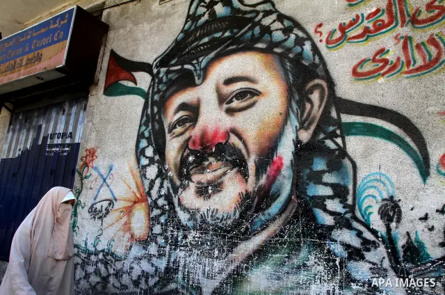 Palestinian woman walks in front of a mural painting of late Palestinian leader Yasser Arafat in central Gaza City on Sep. 17, 2011. The Palestinians are preparing to submit a formal request to become the 194th member of...