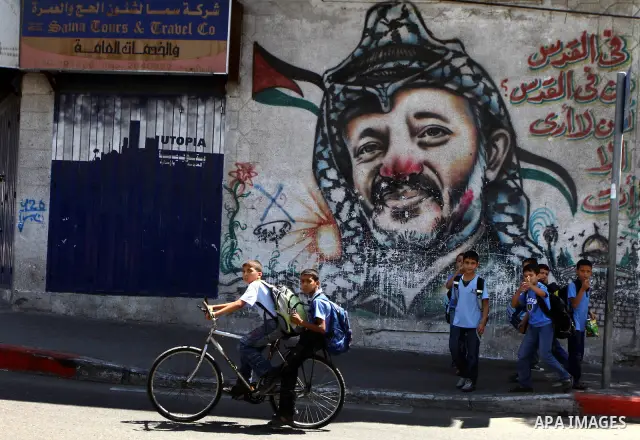 Palestinian students stand in front of a mural painting of late Palestinian leader Yasser Arafat in central Gaza City on Sep. 17, 2011. The Palestinians are preparing to submit a formal request to become the 194th member...