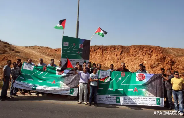 Palestinians hold a poster during a protest against isolating Palestinian villages by the Israeli government and support for the Palestinian statehood bid in the United Nations, in the West Bank village of Biddu, near Ra...