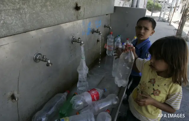 Palestinian children fill bottles from a public water tap at the United Nations Relief and Works Agency (UNRWA) headquarters, in Rafah refugee camp in the southern Gaza strip on September 18, 2011. The Palestinians are p...