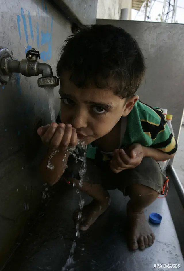Palestinian children fill bottles from a public water tap at the United Nations Relief and Works Agency (UNRWA) headquarters, in Rafah refugee camp in the southern Gaza strip on September 18, 2011. The Palestinians are p...