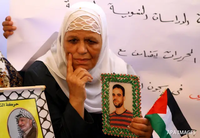 A Palestinian woman holds picture of her prisoned relatives in Israeli jails as they gather in a weekly activity calling for their liberty at the Red Cross headquarters in Gaza City on Sep. 19, 2011. About 7000 prisoners...