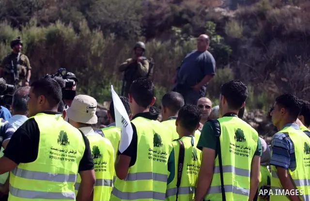 Israeli soldiers stand guard in front of members pro-Palestinian volunteer-based campaign which will intervene and respond to cases of violence towards Palestinians by Jewish settlers in the West Bank, in the West Bank v...