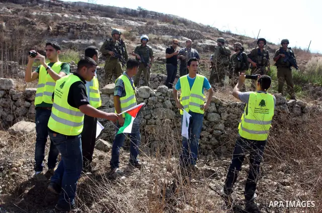Israeli soldiers stand guard in front of members pro-Palestinian volunteer-based campaign which will intervene and respond to cases of violence towards Palestinians by Jewish settlers in the West Bank, in the West Bank v...