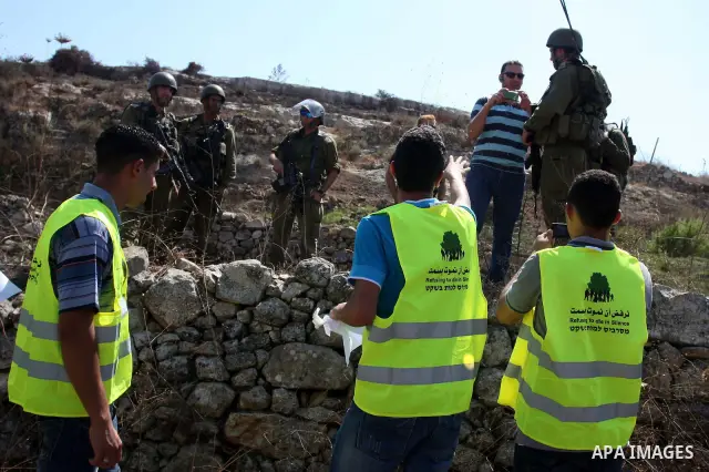 Israeli soldiers stand guard in front of members pro-Palestinian volunteer-based campaign which will intervene and respond to cases of violence towards Palestinians by Jewish settlers in the West Bank, in the West Bank v...